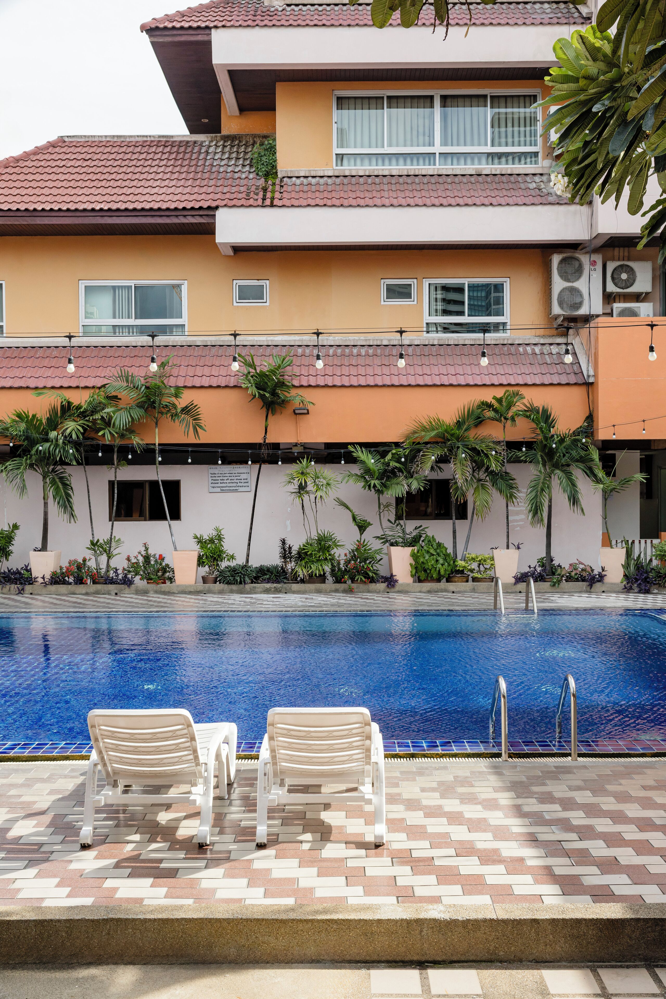A swimming pool with lounge chairs and potted plants.