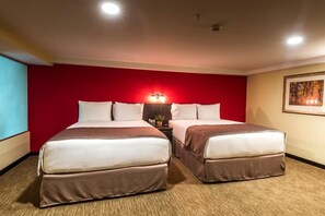 A hotel room with two beds, a red accent wall, a nightstand with a lamp, and a framed picture on the wall. - Exe San Jose Center (San Jose)
