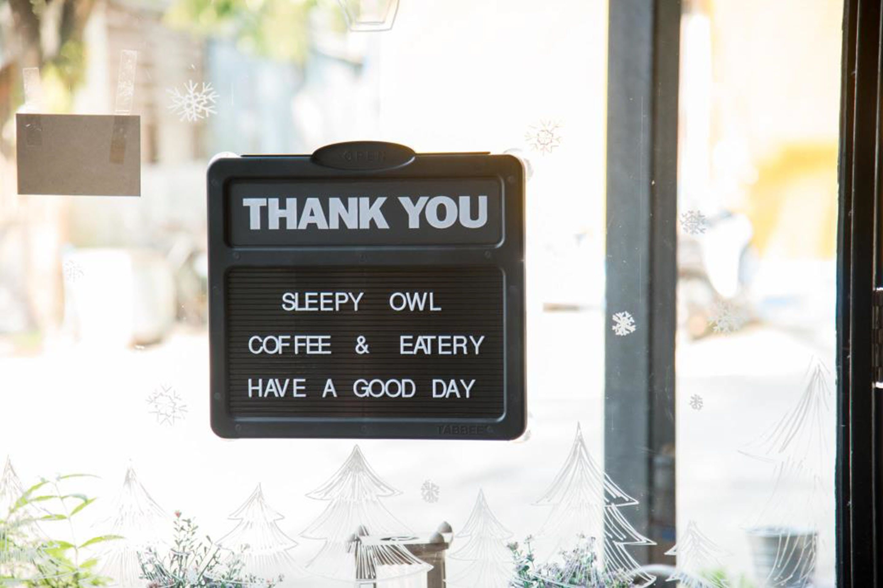 A sign with "THANK YOU" and "SLEEPY OWL COFFEE & EATERY HAVE A GOOD DAY" on a window.