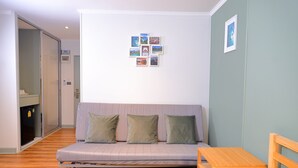 Een kamer met een bank, een klein houten tafeltje en een muur met ingelijste foto's.