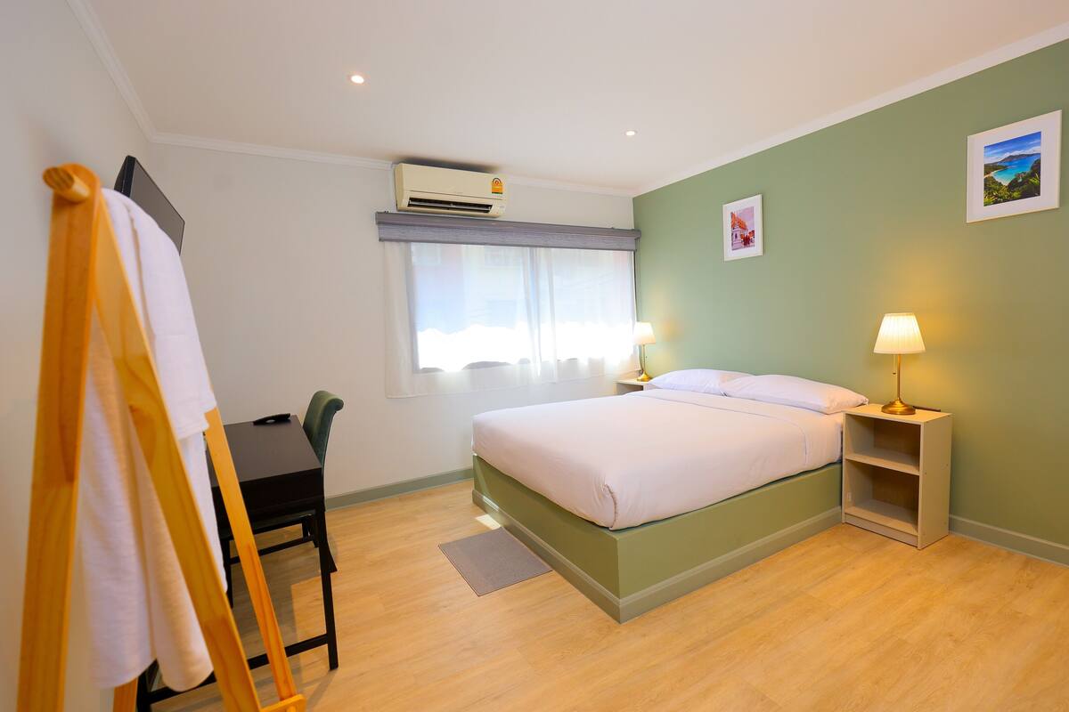 Une chambre d’hôtel équipée d’un lit, de tables de chevet, d’un bureau et d’un appareil de climatisation.
