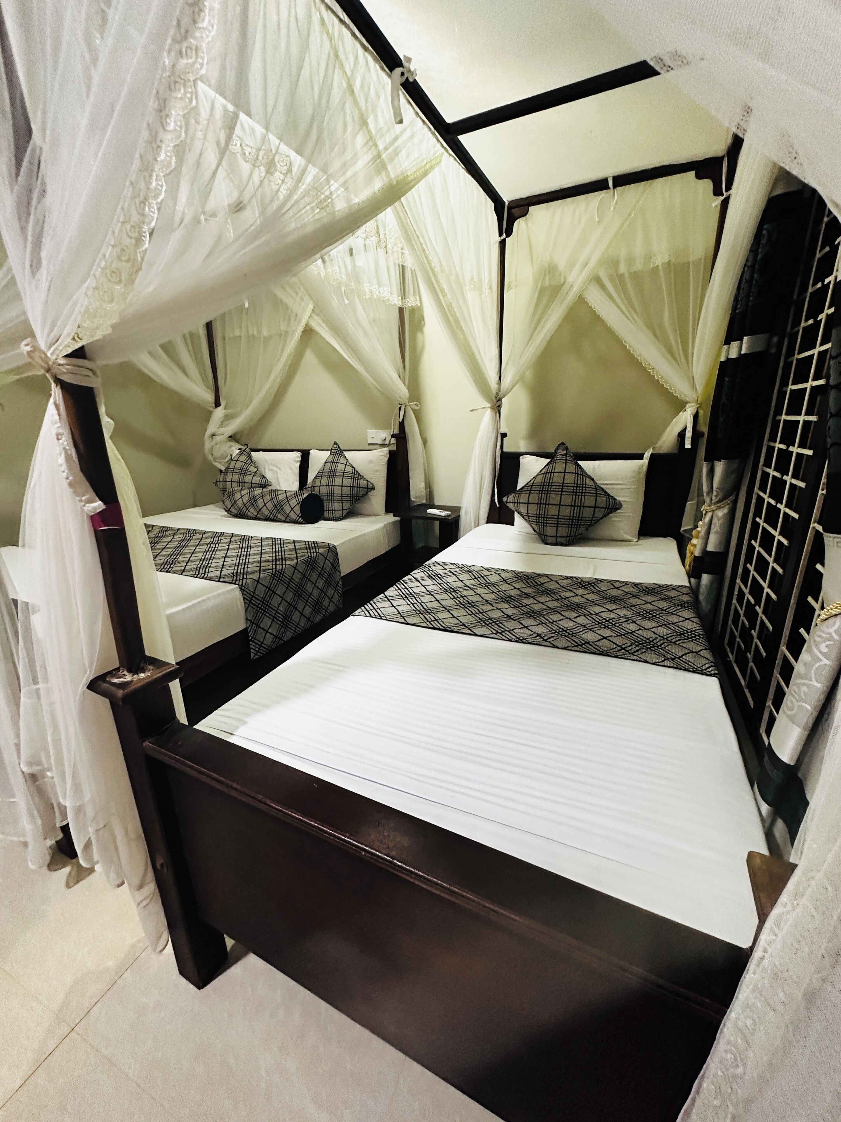 A four-poster canopy bed with a wooden frame, two bedside tables, and a nightstand.