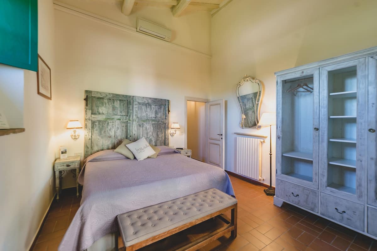 Una camera da letto con un letto, una panca, un armadio e uno specchio.