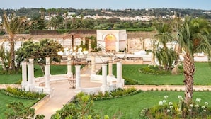 A garden with a central circular area, palm trees, and a pergola.