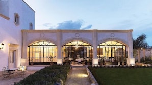 A building with three arched windows and a covered patio area with outdoor seating.