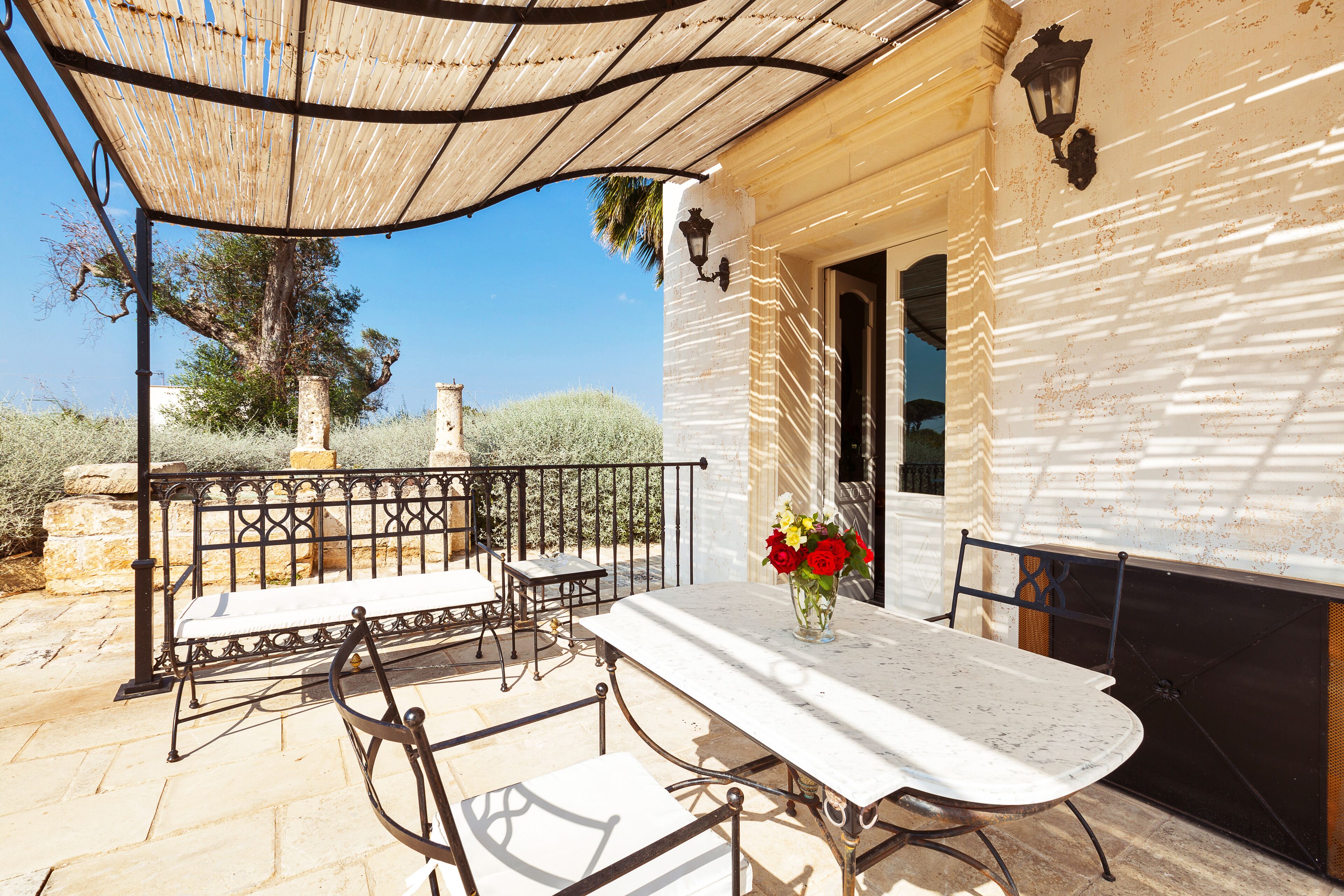 Eine Außenpatio mit Tisch, Stühlen, einer Pergola und einer Wandleuchte.