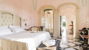 A spacious bedroom with a large bed, a vanity with a mirror, and a checkered floor.