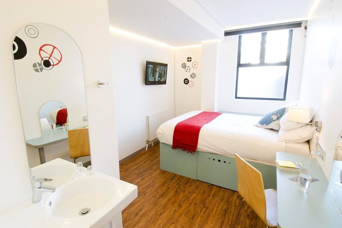 Une chambre à coucher avec un lit, une table de chevet et une fenêtre.
