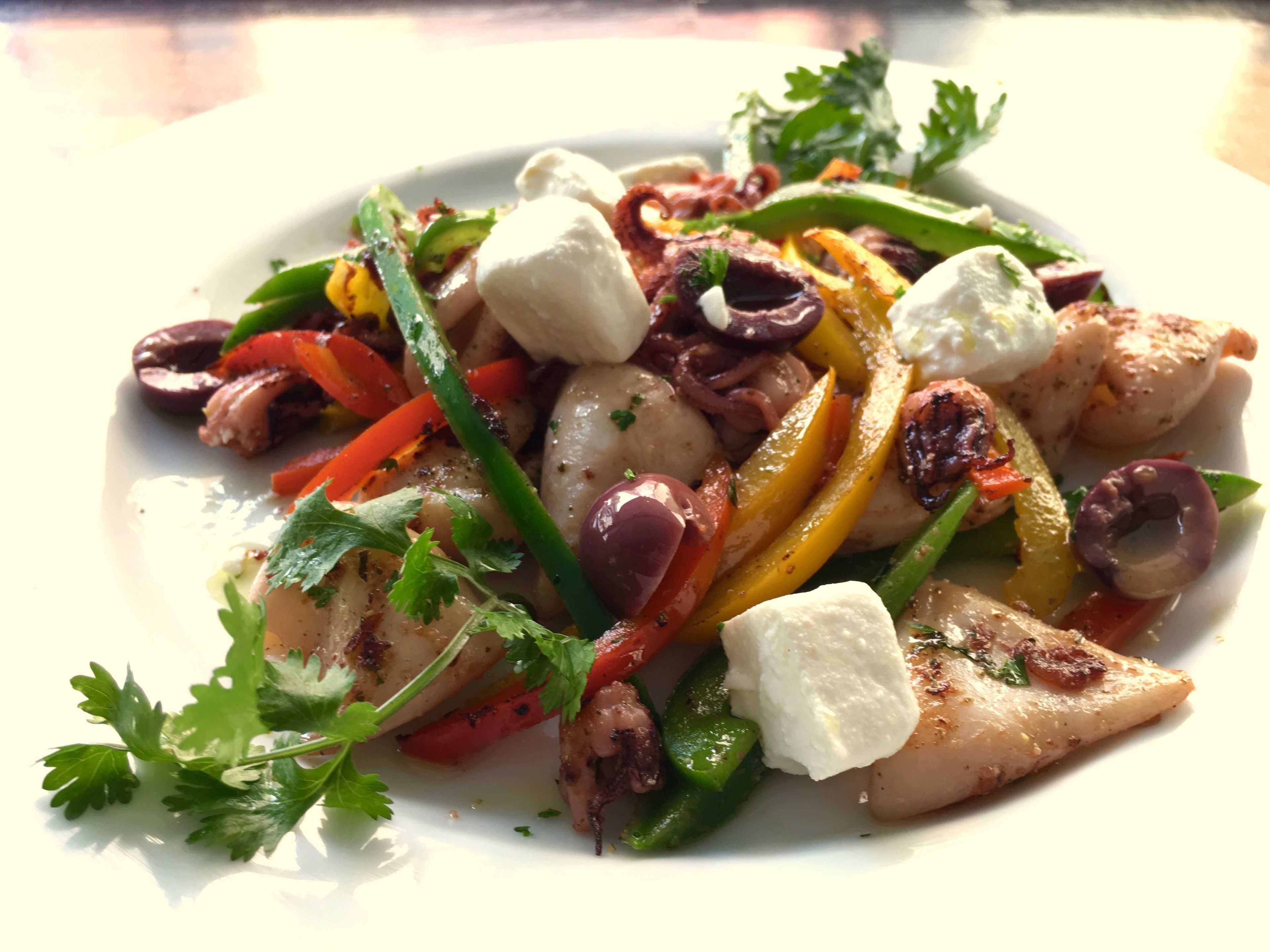A plate of grilled chicken with vegetables and feta cheese.