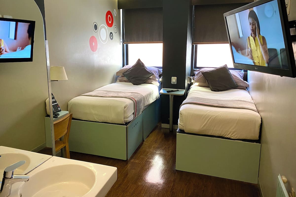 Une chambre d’hôtel avec deux lits, une télévision, une lampe et une salle de bain.