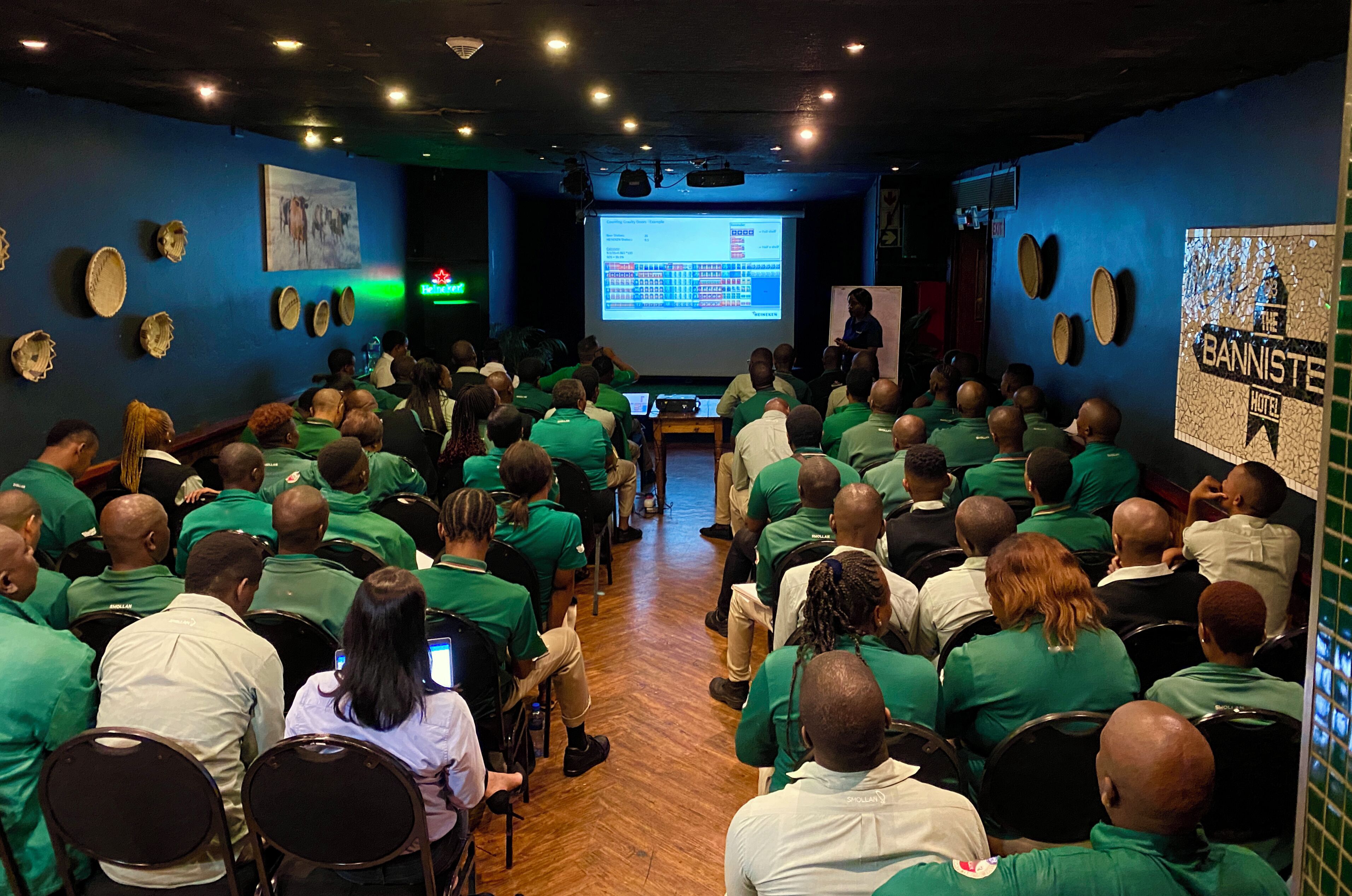 A conference room with attendees seated facing a presentation screen.