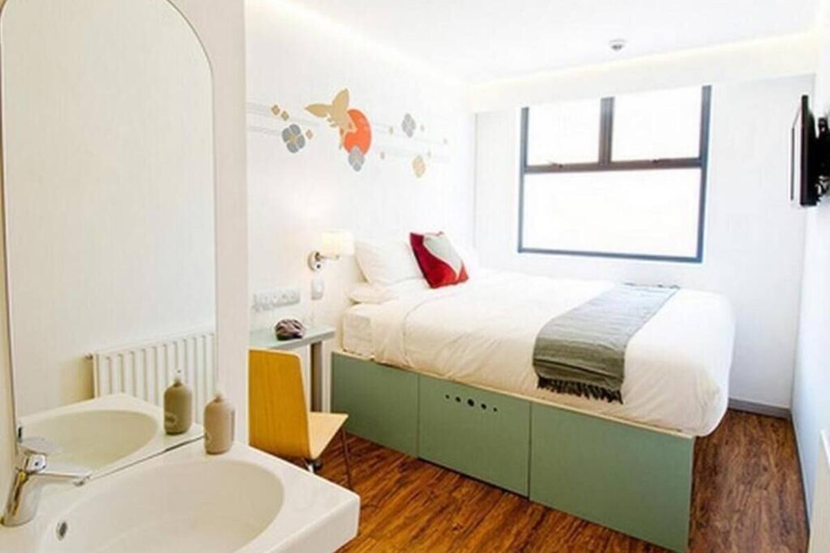 Une chambre moderne avec un grand lit, une table de chevet, un miroir et une fenêtre.