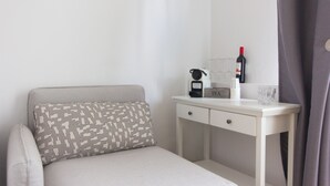 A neatly arranged bedroom with a bed, a bedside table with a coffee maker, a bottle of wine, and a glass. - Tm Suites (Dortmund)