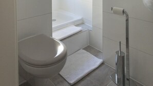 A modern bathroom with a toilet, shower, and sink. - Tm Suites (Dortmund)