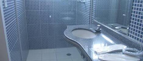 Un baño con lavamanos curvo, paredes con azulejos y un espejo.