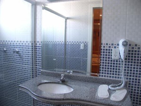 A bathroom with a sink, mirror, and a hairdryer on the wall.
