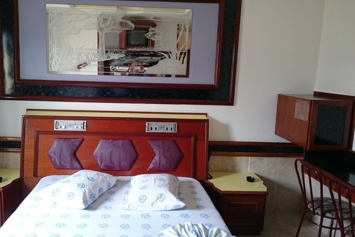 Une chambre d’hôtel comprenant un lit, deux tables de chevet, un bureau et une chaise.