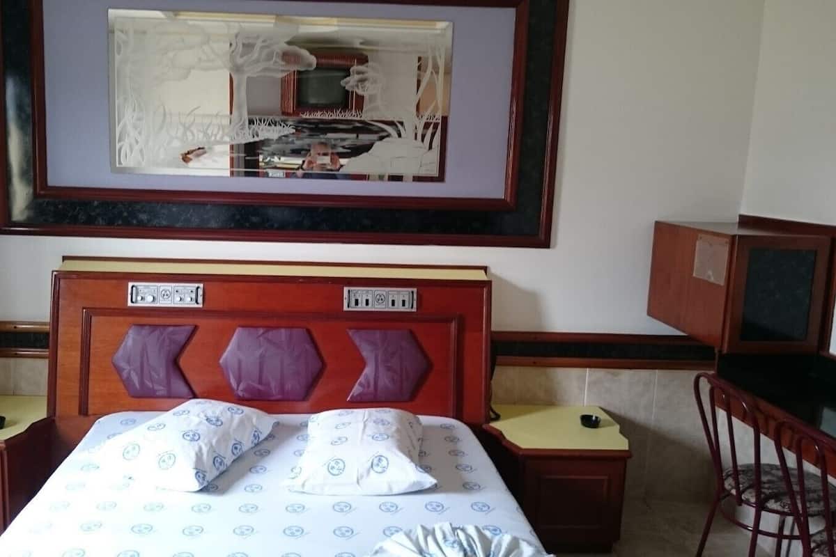 Une chambre d’hôtel comprenant un lit, deux tables de chevet, un bureau et une chaise.