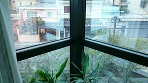 Une fenêtre donnant sur des immeubles d’habitation et un jardin.