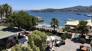 A coastal view with a marina, outdoor seating, and a clear blue sky. - Casamia Boutique Hotel (Bodrum)