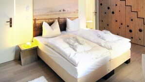 Een moderne slaapkamer met een groot bed, een houten trap en een dakraam.