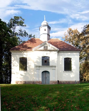 A white church with a steeple, a central entrance, and two symmetrical windows on either side.