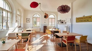A dining area with multiple tables and chairs, arched windows, and a sign indicating the location.