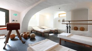 Een spa-ruimte met massagetafels, een massagestoel en een houten vloer.