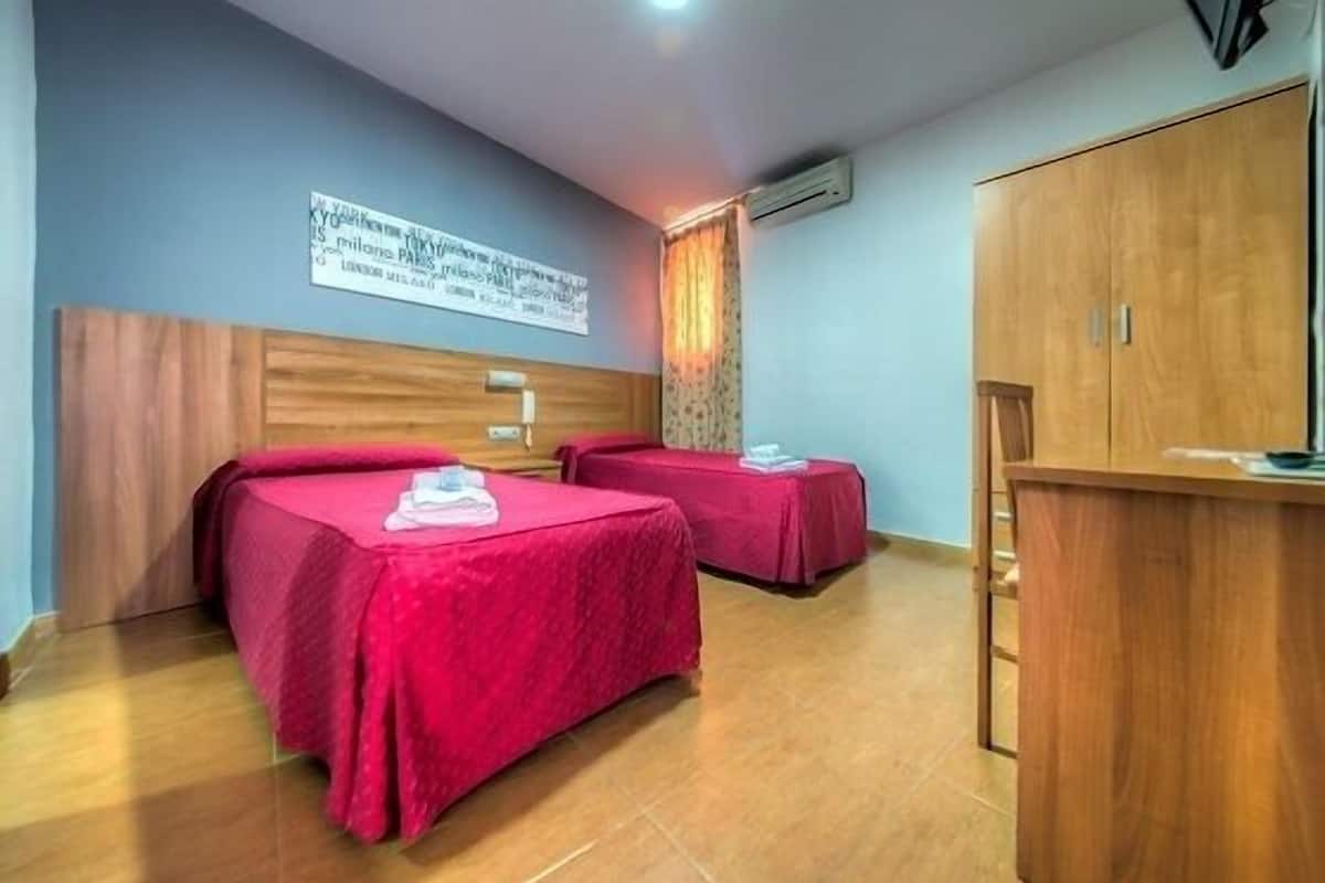 A hotel room with two beds, a wooden wardrobe, and a sign on the wall.