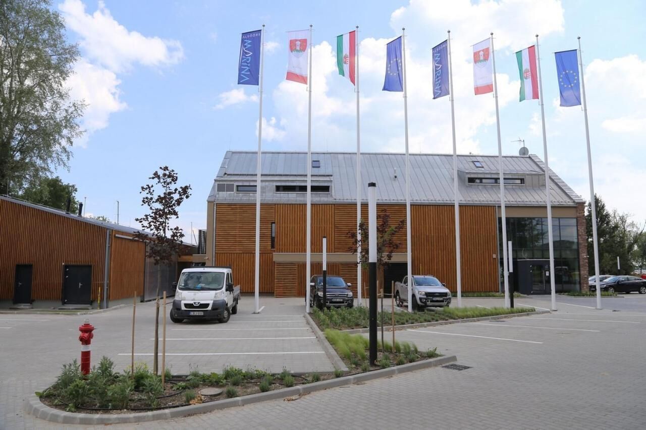 A modern building with a wooden facade and multiple flags, including the European Union flag.