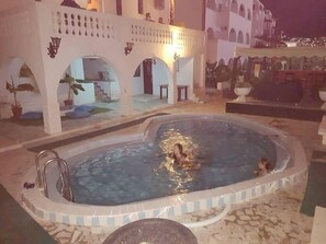 Alberca al aire libre, sombrillas en la alberca y camastros