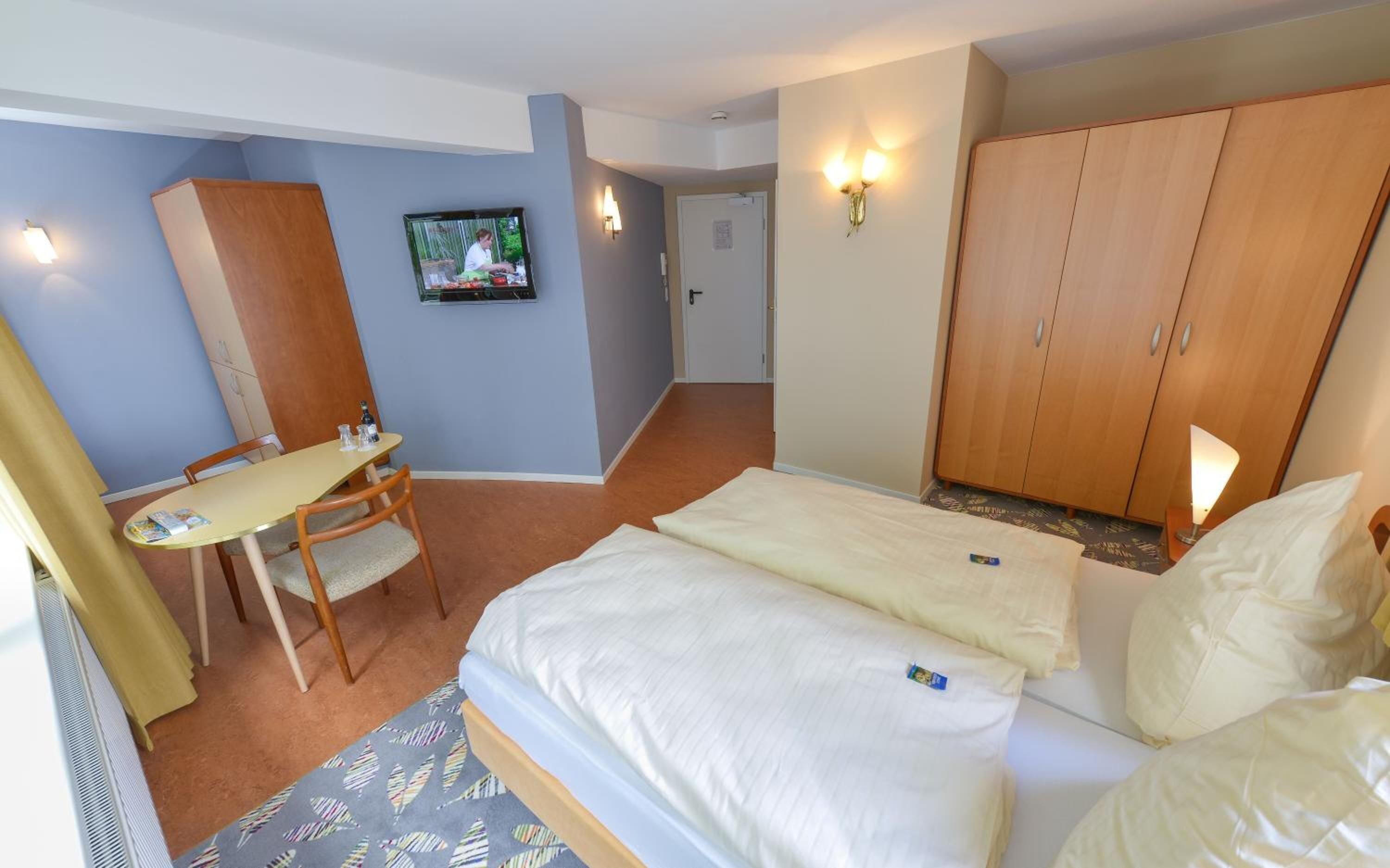 Ein Hotelzimmer mit Bett, Schreibtisch, Stuhl und Kleiderschrank.