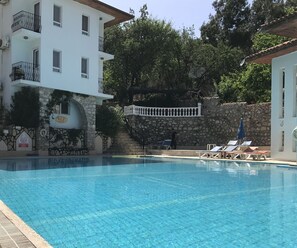 Una piscina al aire libre, sombrillas, tumbonas
