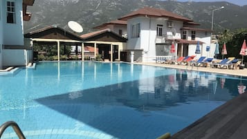 Una piscina al aire libre, sombrillas, tumbonas