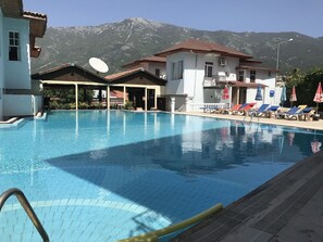 Una piscina al aire libre, sombrillas, tumbonas
