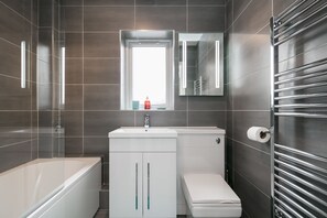 A modern bathroom with a bathtub, toilet, and sink. - Bluestone Apartments - Didsbury (Manchester)