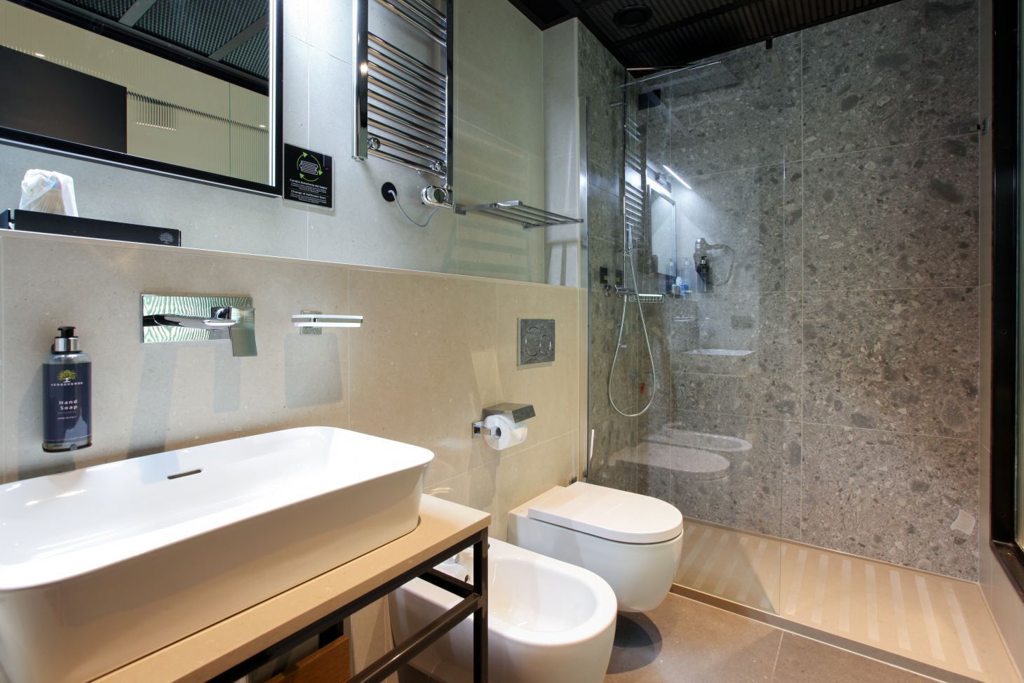 A modern bathroom with a large sink, toilet, and glass-enclosed shower.