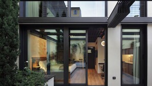 A modern house with large glass doors leading to a living area with a sofa and a dining table. - Versoverde Alzaia Naviglio Grande (Milan)