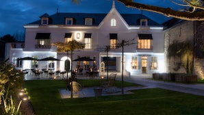 A large, white building with a reception and restaurant area, featuring outdoor seating and a well-maintained lawn. - Bel Ami (Pacy-sur-Eure)
