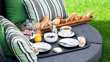 Un montaje para picnic con pan, pasteles, una taza de té y alimentos para el desayuno en una bandeja.