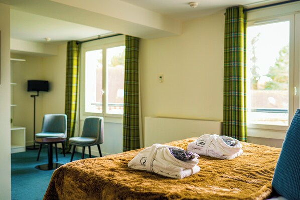 A hotel room with a bed, two chairs, a desk, and a television. - Bel Ami (Pacy-sur-Eure)