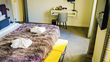 A hotel room with a bed, a desk, a chair, and a TV.