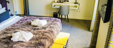 A hotel room with a bed, a desk, a chair, and a TV.