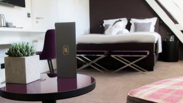 A modern hotel room with a bed, a desk, a chair, and a small potted plant.