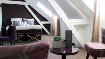 Ein modernes Schlafzimmer mit schrägen Wänden, einem Bett, einem kleinen Tisch und zwei Stühlen.
