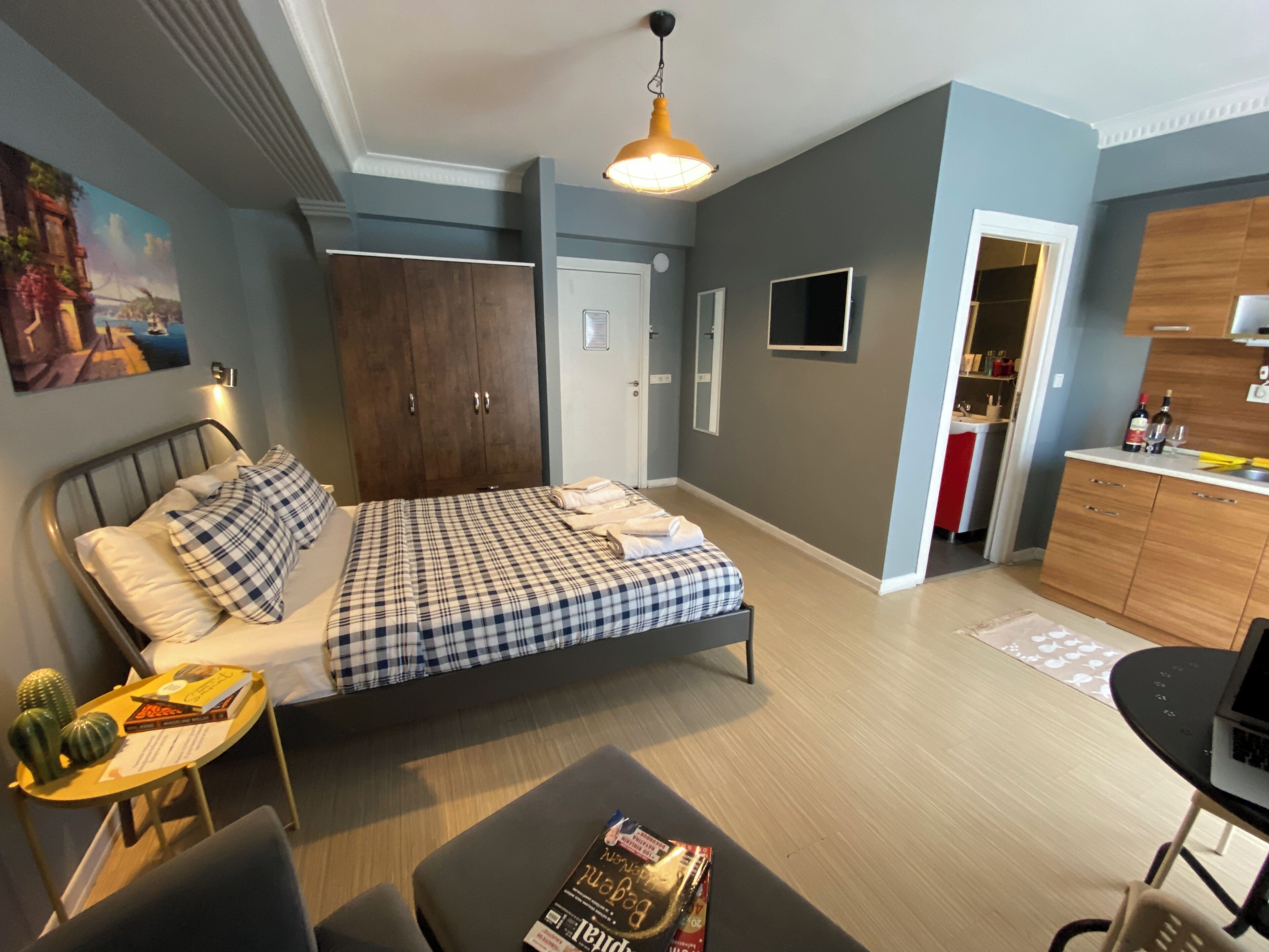 Un dormitorio moderno con cama, mesitas de noche, armario y kitchenette.