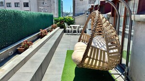 A rooftop terrace with a hanging chair, potted plants, and a view of the cityscape. - Flats Company - Karakoy Apartment (Istanbul)