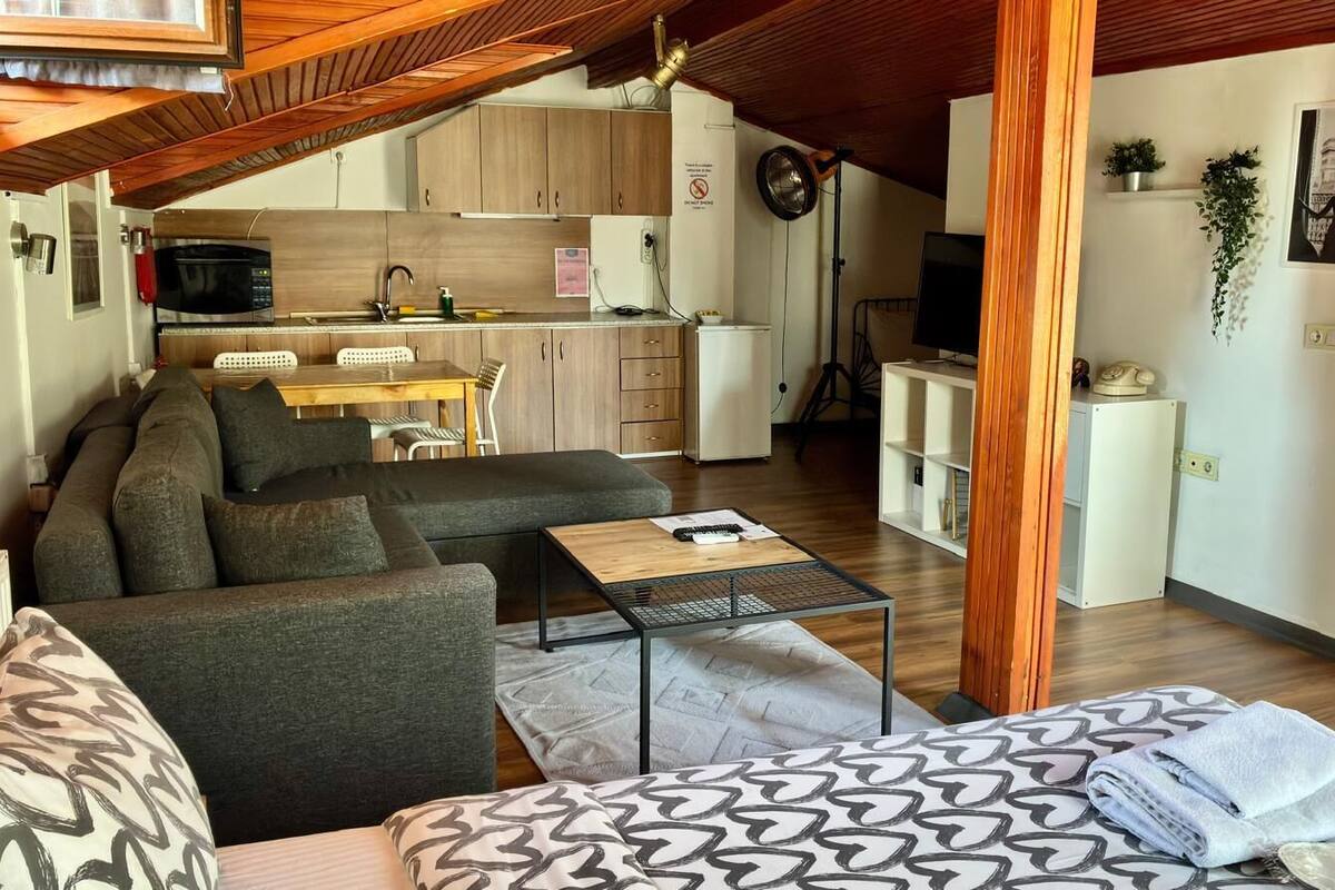 A compact living space with a sofa, a small table, a kitchen area with a microwave, and a dining table.