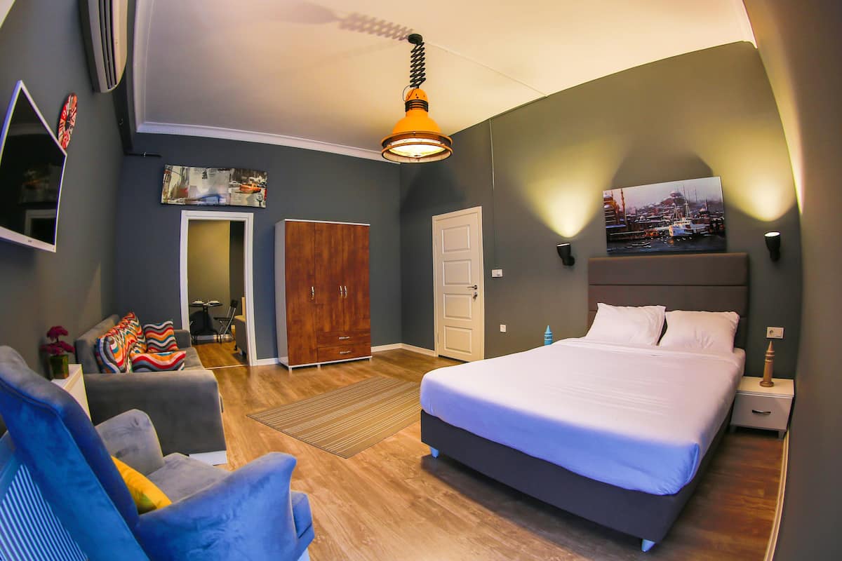 A modern bedroom with a large bed, a desk, and a chair.