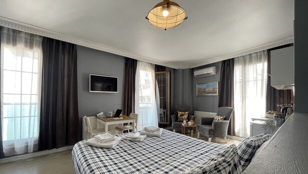 A modern hotel room with a large bed, a desk with a computer, a chair, and a sofa. - Flats Company - Karakoy Apartment (Istanbul)